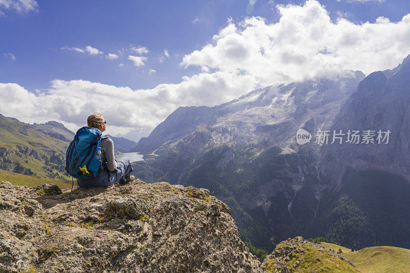 意大利北部Dolomites的Viel dal Pan小路上，一位老妇人正在欣赏美丽的Fedaia湖和Marmolada湖。